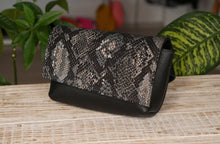 Kép betöltése a galériamegjelenítőbe: Borsetă elegantă din piele naturală neagră cu model de șarpe, așezată pe suprafață, cu închidere cu fermoar și curea reglabilă, geantă de talie pentru femei, ideală pentru oraș și evenimente