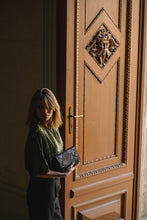 Kép betöltése a galériamegjelenítőbe: Borsetă din piele neagră cu model modern, purtată crossbody de o femeie, vedere frontală