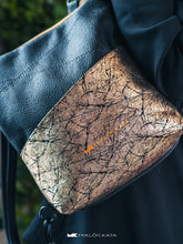 Kép betöltése a galériamegjelenítőbe: Fotografie de detaliu a unui rucsac din piele, cu buzunar mare auriu în față.