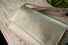 Kép betöltése a galériamegjelenítőbe: Borsetă elegantă din piele aurie, fotografie detaliu apropiat exterior, cu închidere magnetică și curea reglabilă, fundal alb