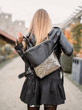 Kép betöltése a galériamegjelenítőbe: Fotografie urbană cu un rucsac din piele, decorat cu un buzunar frontal mare, aurit.

