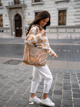 Load image into Gallery viewer, Femeie care ține o geantă shopper bej pe o stradă din oraș.

