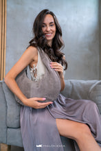 Load image into Gallery viewer, Femeie care ține o geantă gri, așezată pe o canapea, cu fundal estompat.

