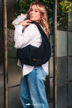 Load image into Gallery viewer, O femeie cu o geantă neagră din piele întoarsă pe umăr.

